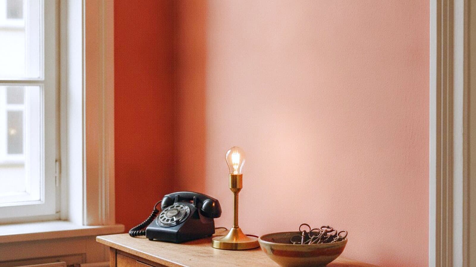 Flurtisch einer Altbauwohnung, daneben eine brennende Lampe und ein Telefon
